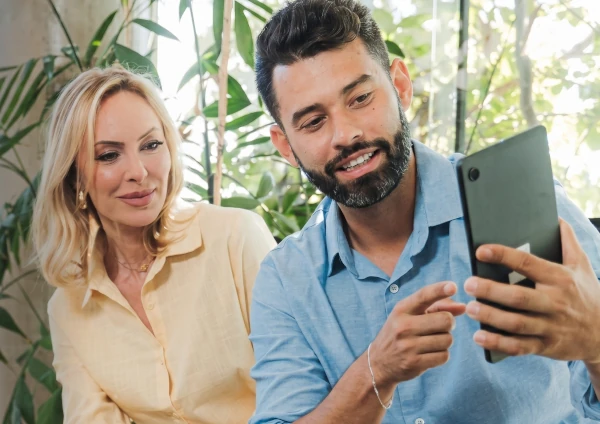 Um homem e uma mulher sorrindo olhando para um tablet