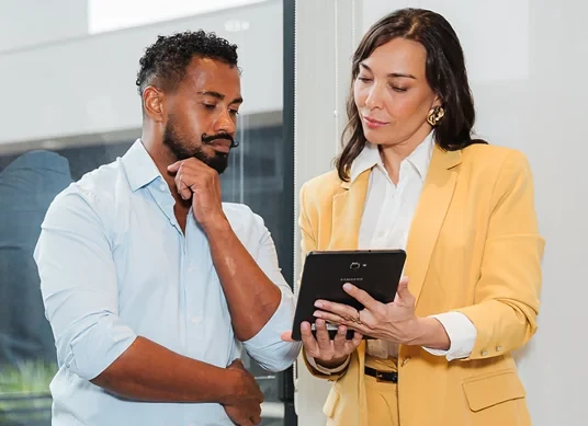 Imagem de um homem e uma mulher olhando para um tablet