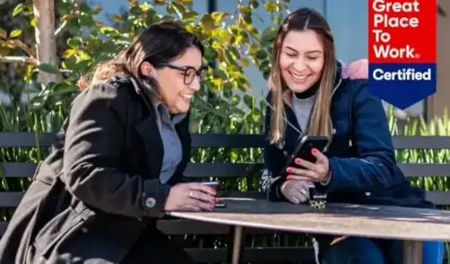 Duas mulheres sorrindo enquanto olham um celular