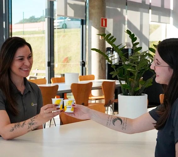 Duas funcionárias tomando café na área de convivência da empresa