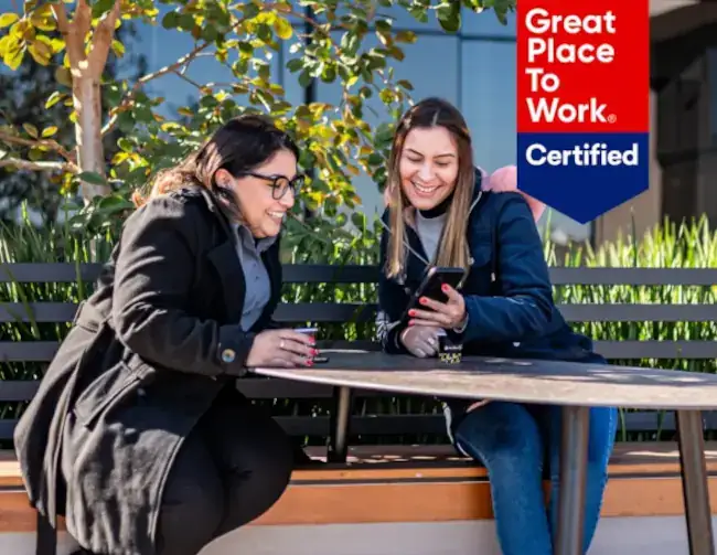 Duas mulheres sorrindo enquanto olham um celular