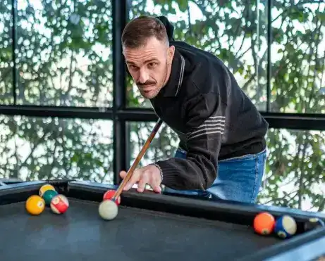 Funcionário jogando sinuca na área de lazer da empresa