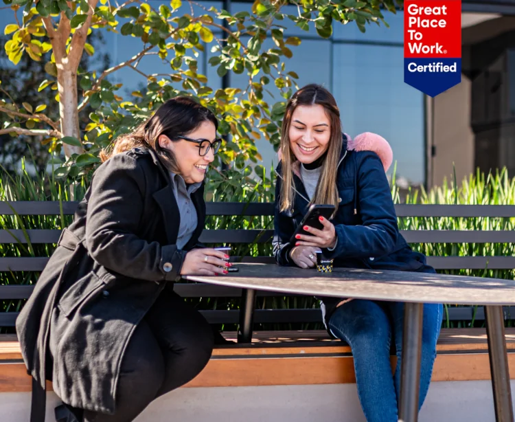 Duas mulheres sorrindo enquanto olham um celular