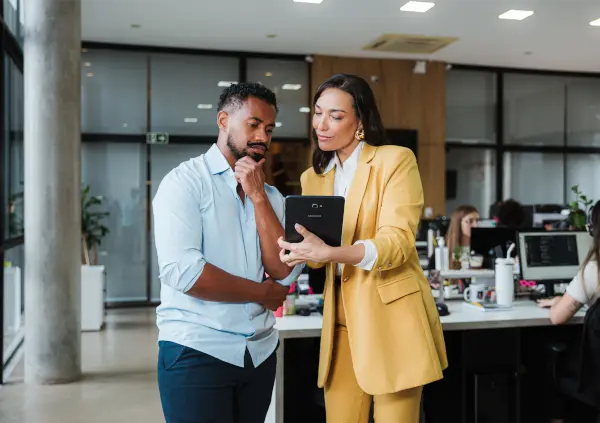 Um homem e uma mulher sorrindo olhando para um tablet