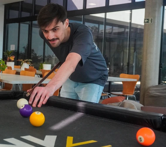 Funcionário jogando sinuca na área de lazer da empresa