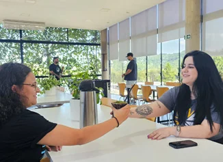 Duas funcionárias tirando uma selfie na área de convivência da empresa